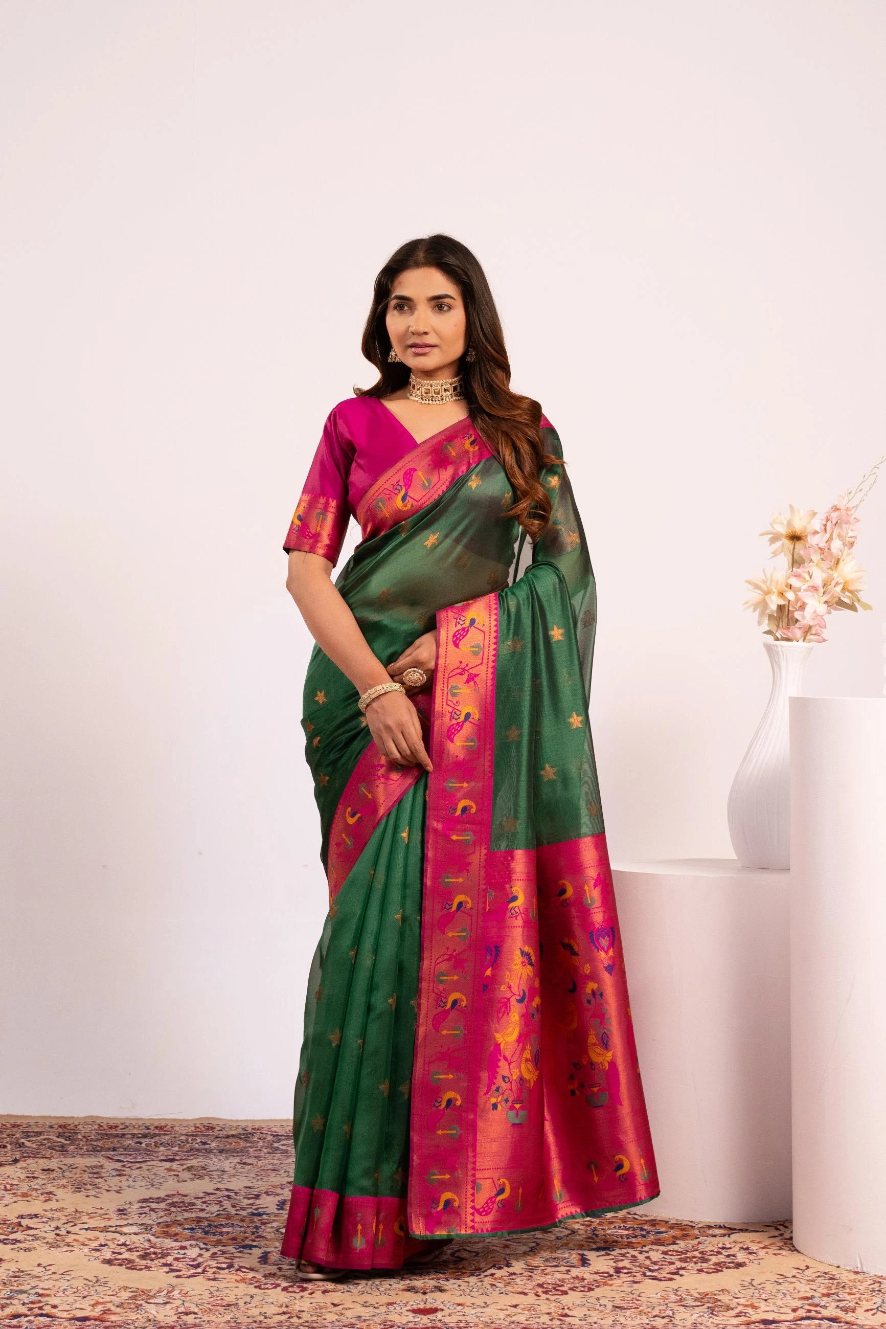 Woman wearing a green and pink saree with a white background